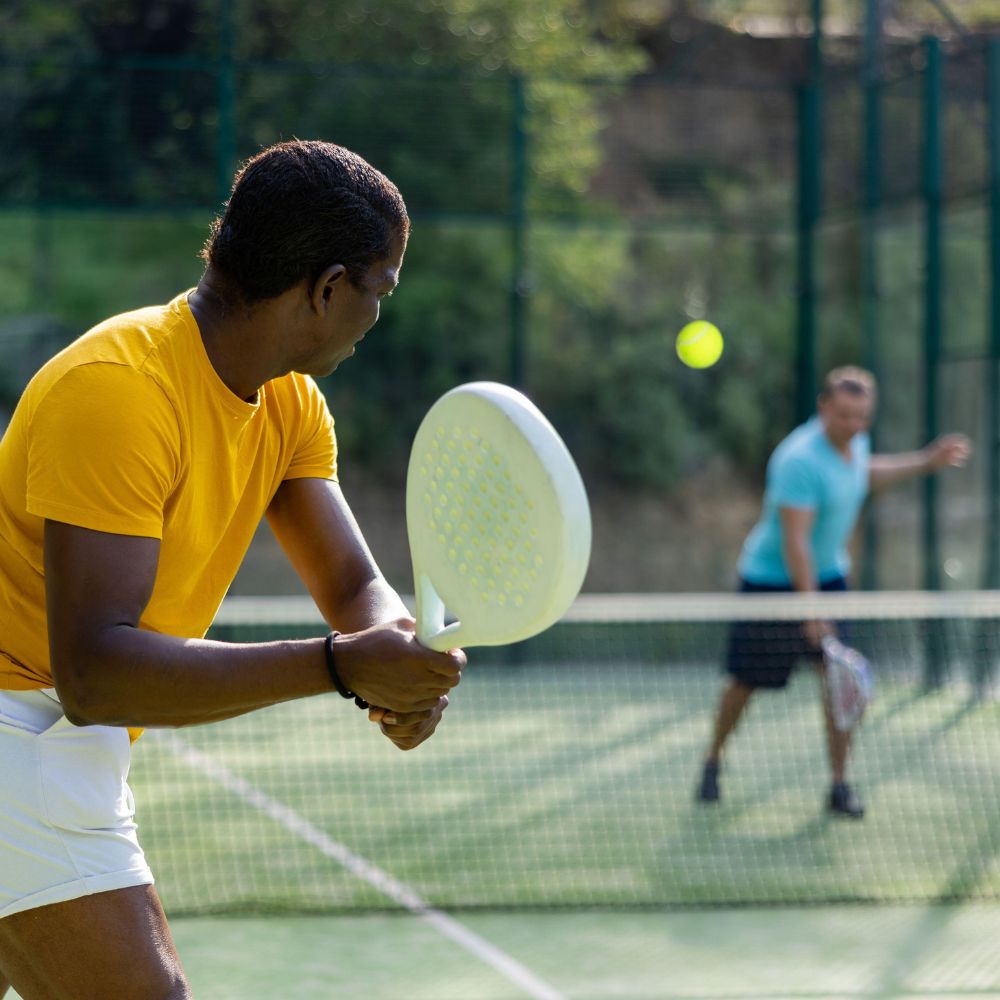 Two people playing paddle tennis on a court with a blurred background